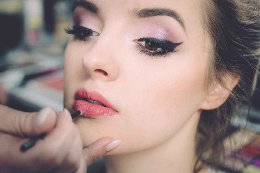A makeup artist applying lipstick to a client